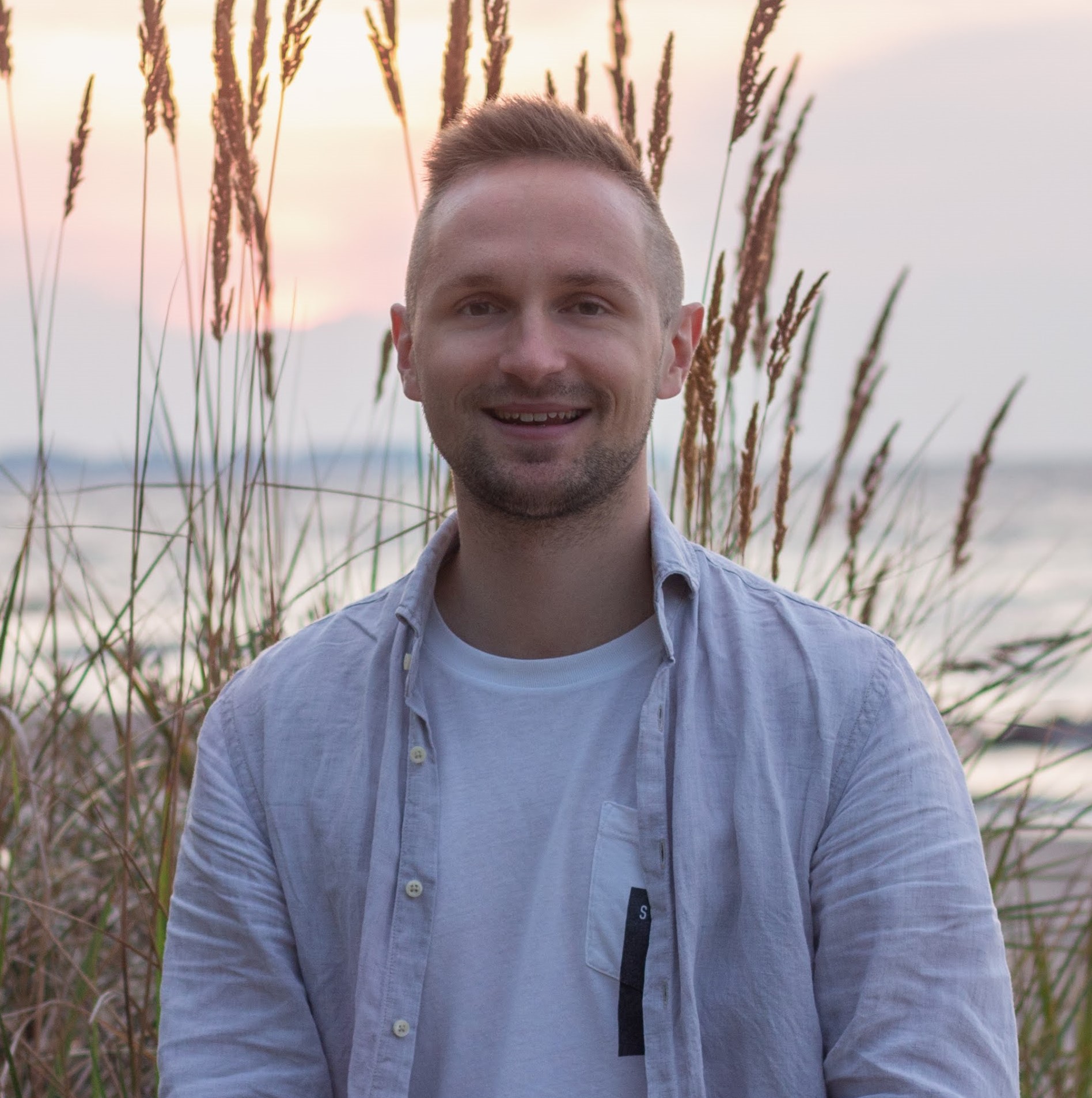 Peer sitzt am Strand und lächelt in die Kamera